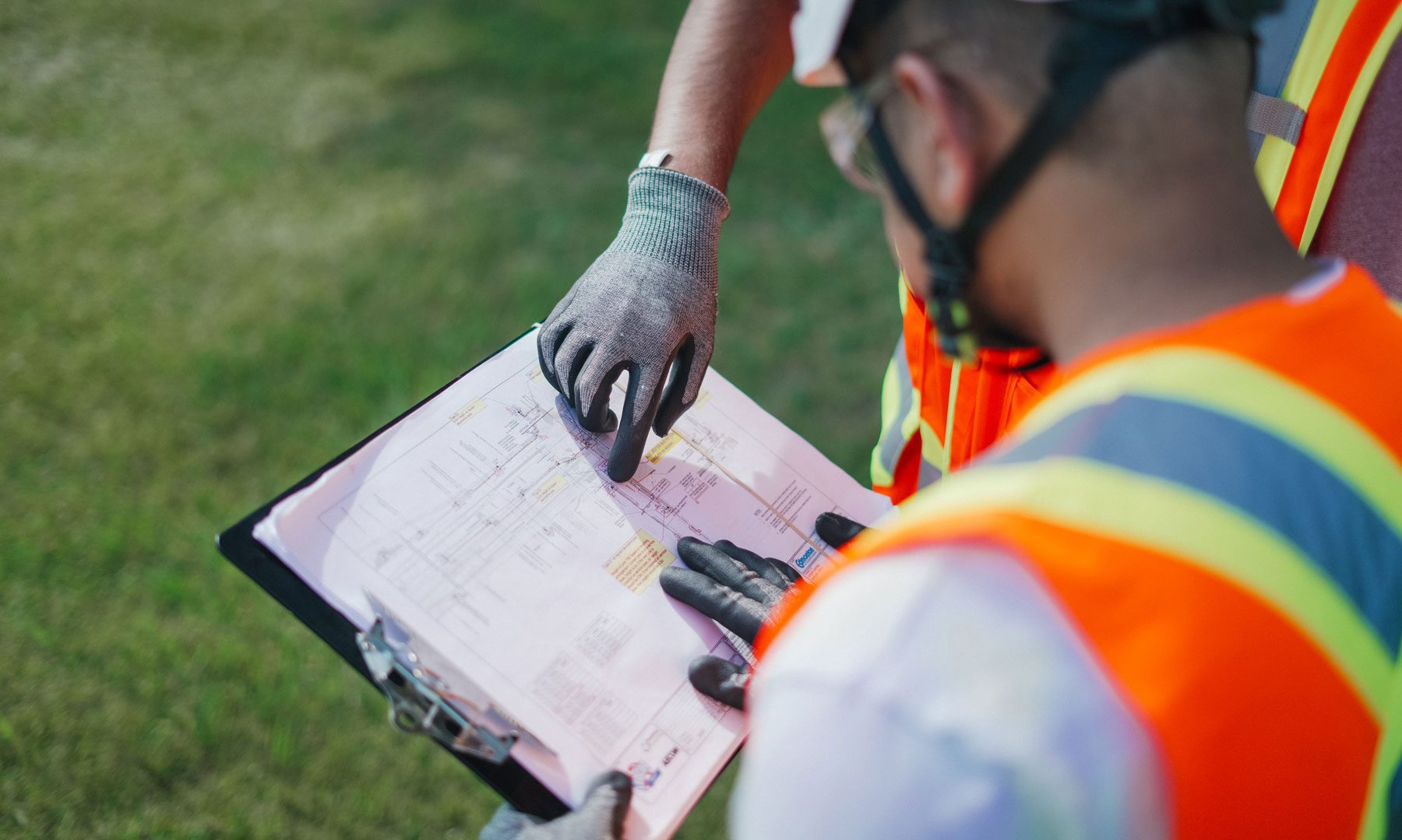 Construction workers reviewing site plans outdoors.